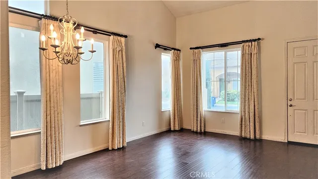 an empty room with wooden floor door and windows