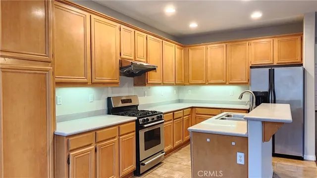 a kitchen with stainless steel appliances granite countertop a stove a sink a refrigerator white cabinets and wooden floor