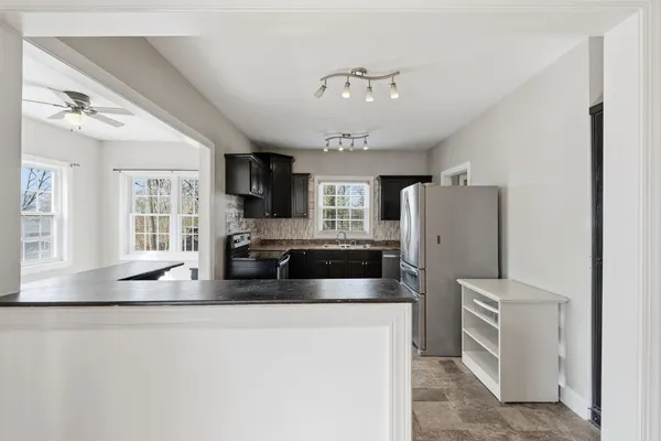 a kitchen with stainless steel appliances granite countertop a stove top oven a sink dishwasher a dining table and chairs with wooden floor