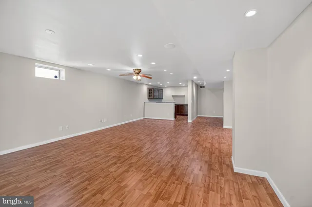 a view of a big room with wooden floor and a kitchen