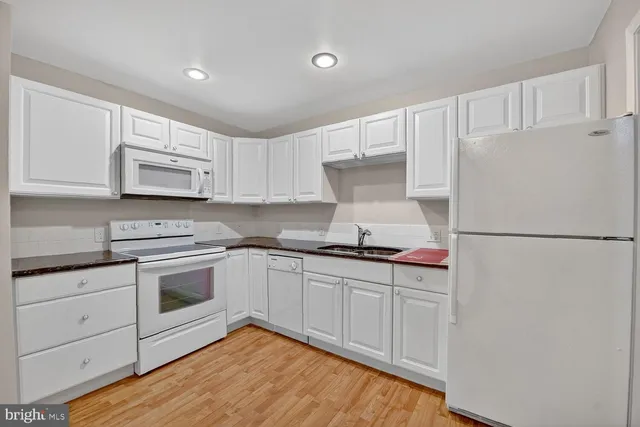 a kitchen with white cabinets and white appliances