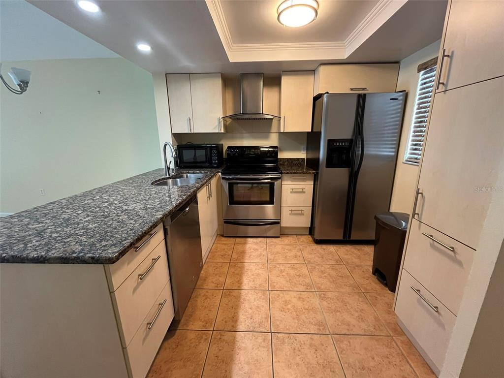25225 Rampart Boulevard, Unit 2107 Punta Gorda, FL 33983 - Photo 2 of 10 a kitchen with granite countertop a refrigerator and a stove top oven