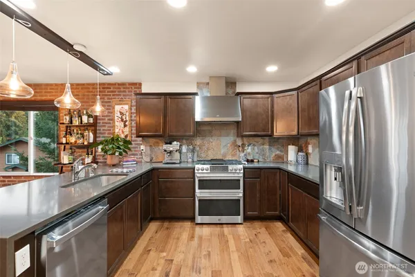 a kitchen with stainless steel appliances granite countertop a sink and wooden cabinets