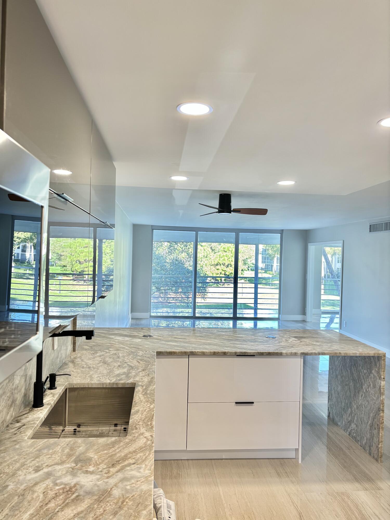 545 Oaks Lane, Unit 201 Pompano Beach, FL 33069 - Photo 6 of 22 a view of a kitchen with kitchen island a sink wooden floor and a large window