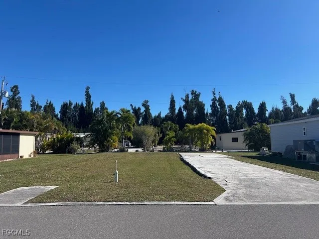 a view of a white house with a yard and tree in front of it