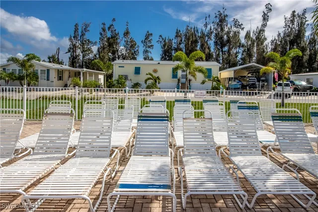 a view of swimming pool with seating space and trees in the background