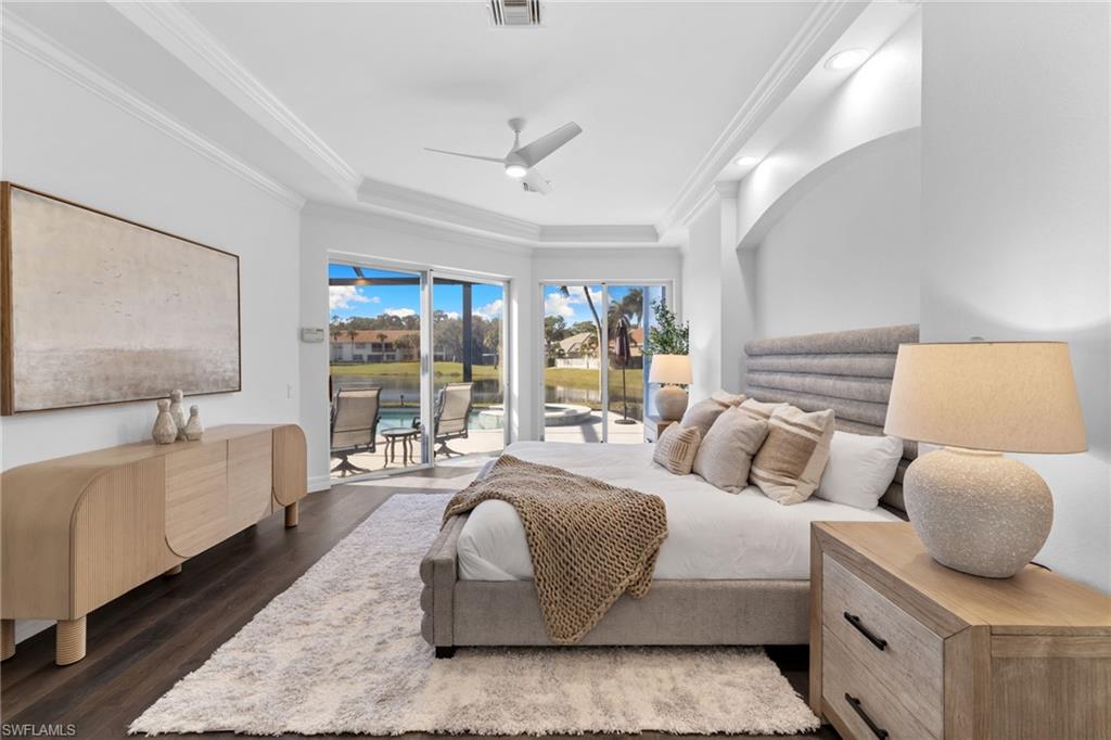 1624 Manchester Court Naples, FL 34109 - Photo 2 of 49 Bedroom featuring access to exterior, dark wood-style floors, ceiling fan, ornamental molding, and a tray ceiling
