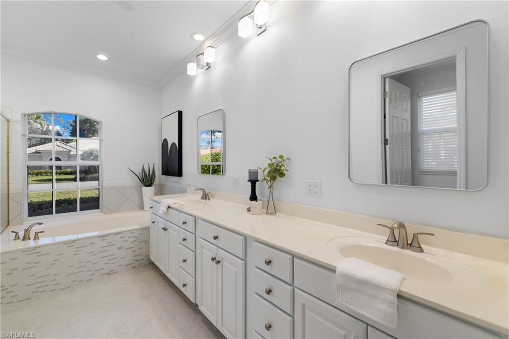 1624 Manchester Court Naples, FL 34109 - Photo 25 of 49 Full bathroom featuring a garden tub, double vanity, crown molding, light tile patterned floors, and tiled shower