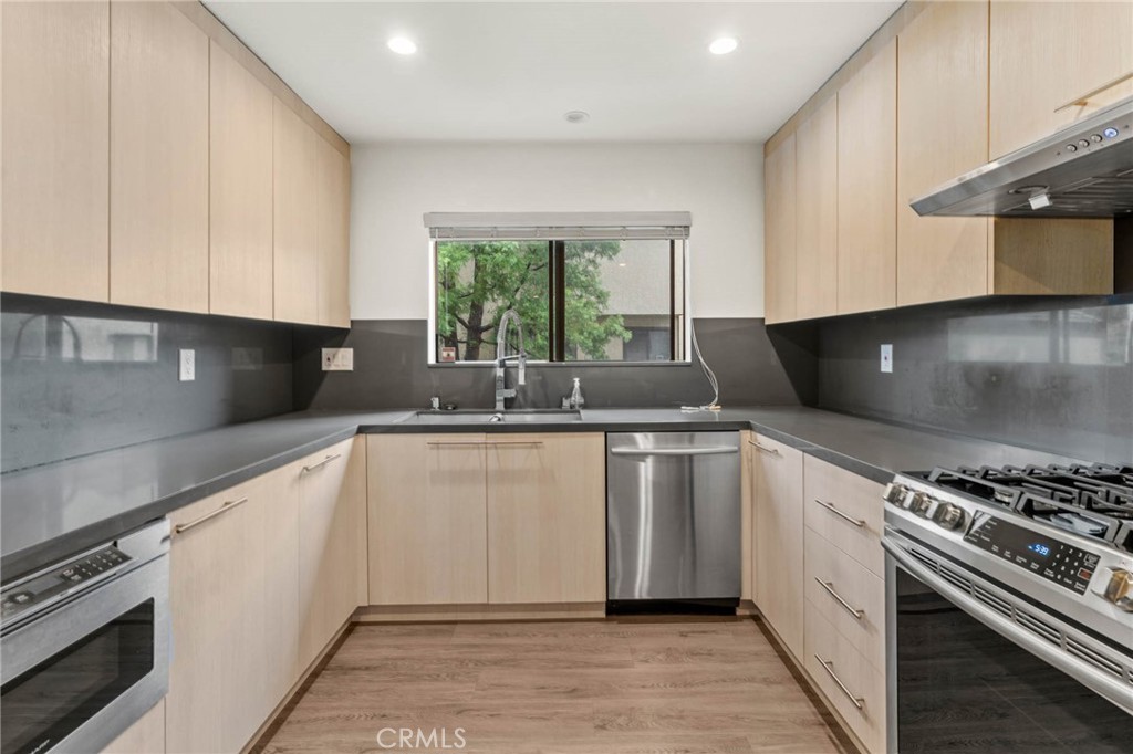 5757 Owensmouth Avenue, Unit 1 Woodland Hills, CA 91367 - Photo 24 of 42 a kitchen with granite countertop a sink stainless steel appliances a counter top space cabinets and a window