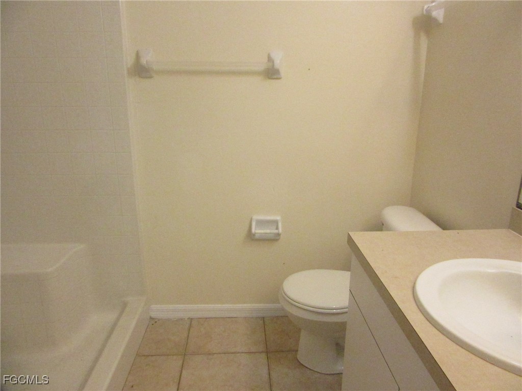 4546 28th Street Southwest Lehigh Acres, FL 33973 - Photo 7 of 9 a white toilet sitting next to a white sink and vanity