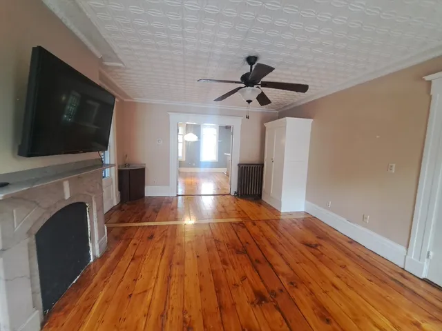 a view of empty room with wooden floor and fireplace