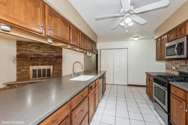 a kitchen with stainless steel appliances granite countertop a sink a stove top oven a chimney cabinets and dining table