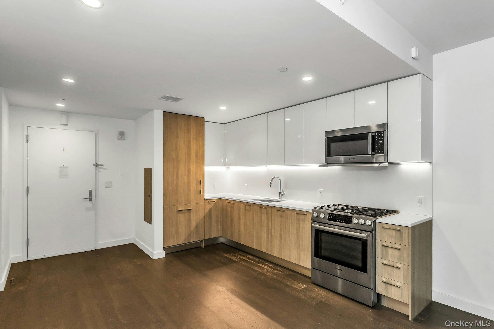 131-03 40 Road, Unit 10E Queens, NY 11354 - Photo 5 of 15 Kitchen with modern cabinets, appliances with stainless steel finishes, dark wood finished floors, light countertops, and recessed lighting