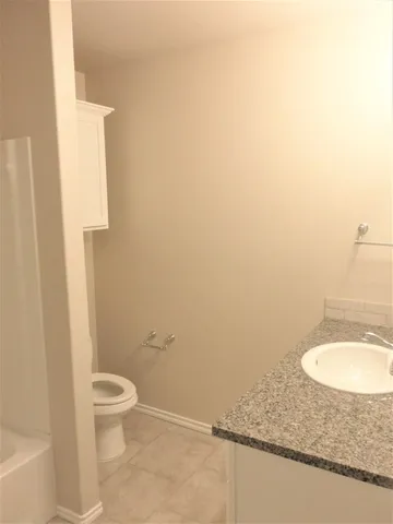 a bathroom with a granite countertop toilet and a sink