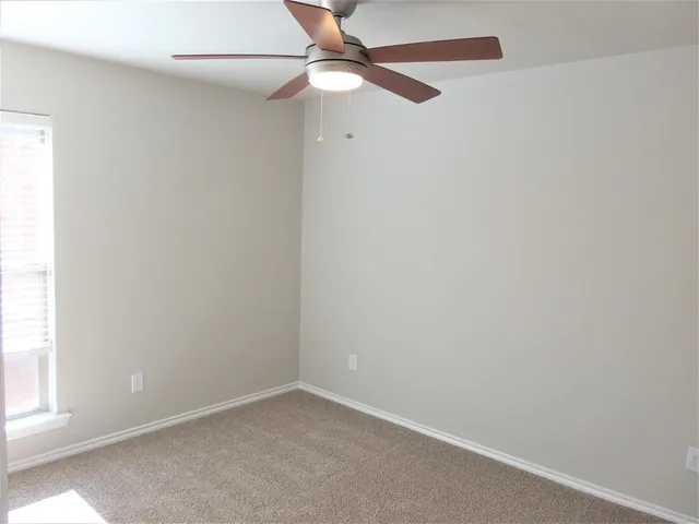 an empty room with a window and a fan