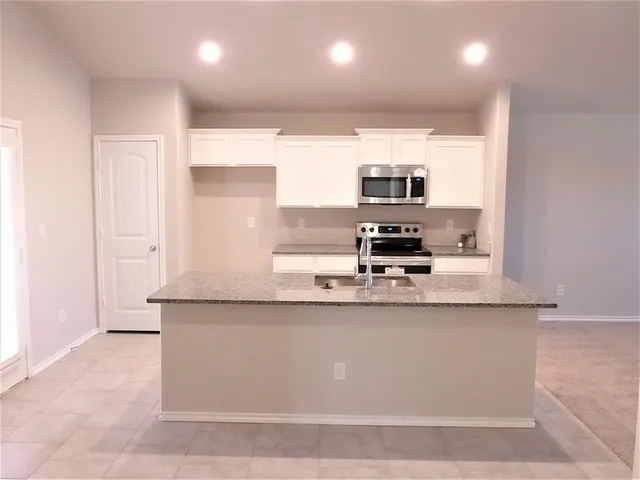 a kitchen with stainless steel appliances granite countertop a sink a stove and a refrigerator