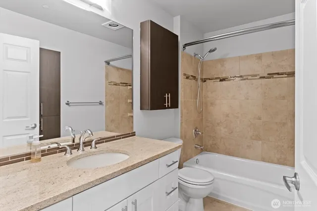 a bathroom with a granite countertop bathtub shower sink vanity mirror and toilet