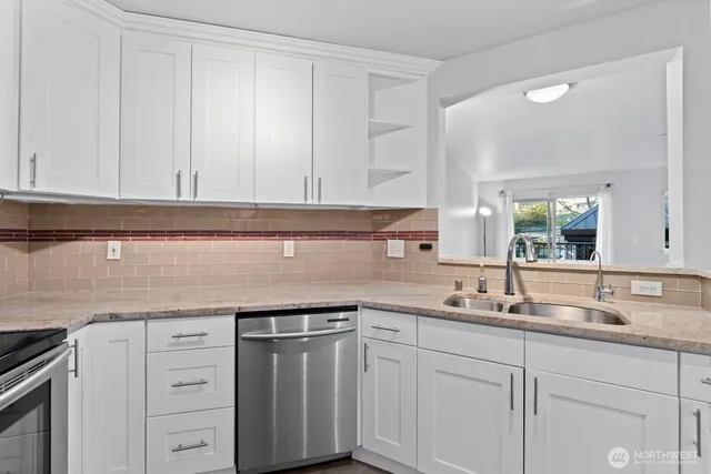 a kitchen with white cabinets and sink