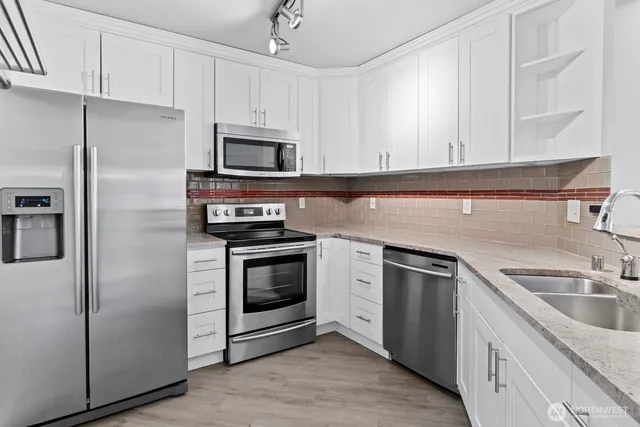 a kitchen with stainless steel appliances granite countertop a refrigerator sink and stove