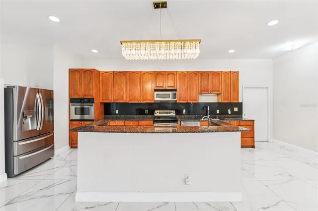 a large white kitchen with stainless steel appliances kitchen island granite countertop a large counter top and a stove