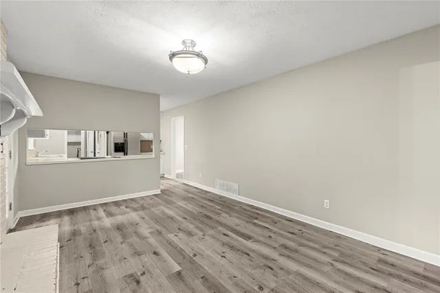 a view of kitchen and empty room with wooden floor