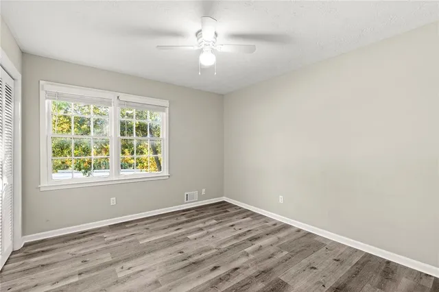 an empty room with wooden floor and windows