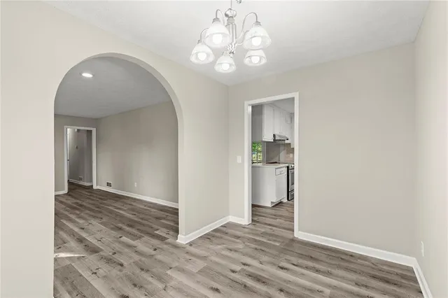 a view of a hallway with wooden floor and a kitchen