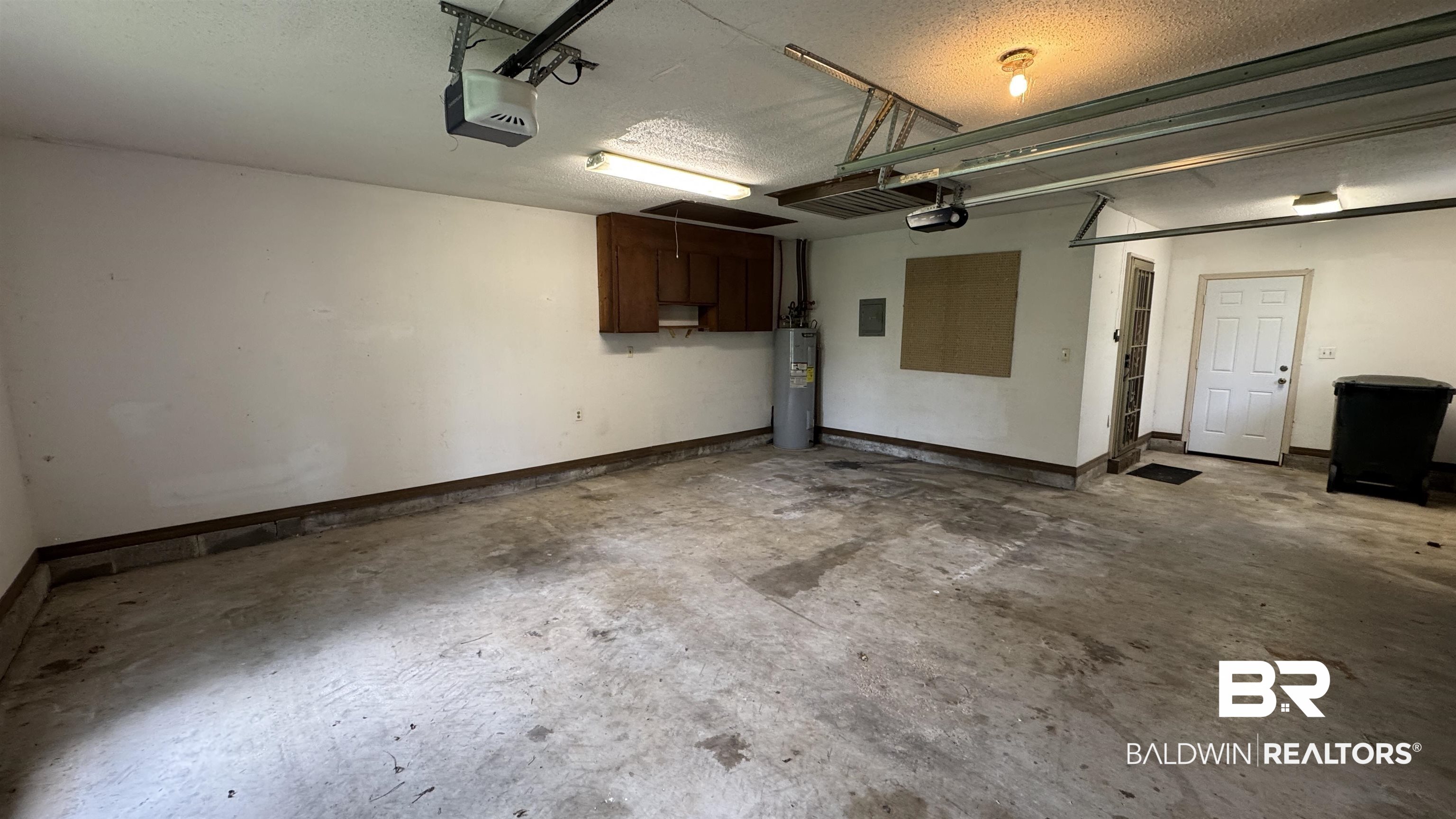 33370 Highway 98 Lillian, AL 36549 - Photo 40 of 58 Two-car garage featuring concrete flooring, overhead lighting, garage door opener mechanisms, a water heater, and built-in cabinetry