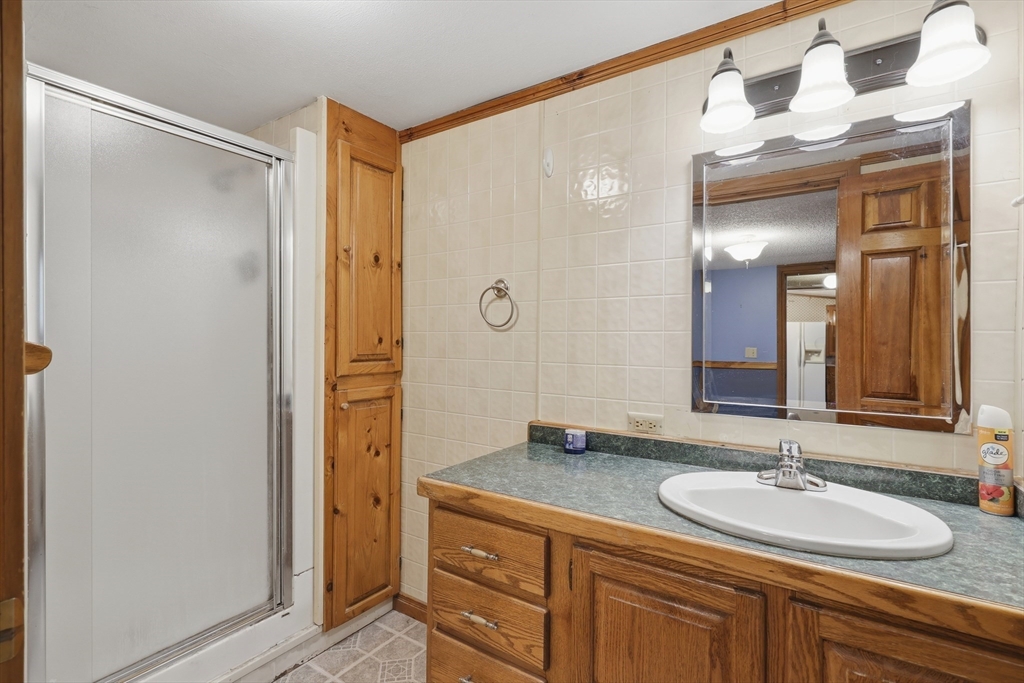 987 Patriots Road Templeton, MA 01468 - Photo 22 of 39 a bathroom with a granite countertop sink a mirror and a shower