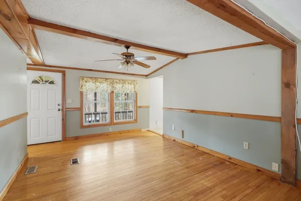 a view of an empty room with wooden floor and a window