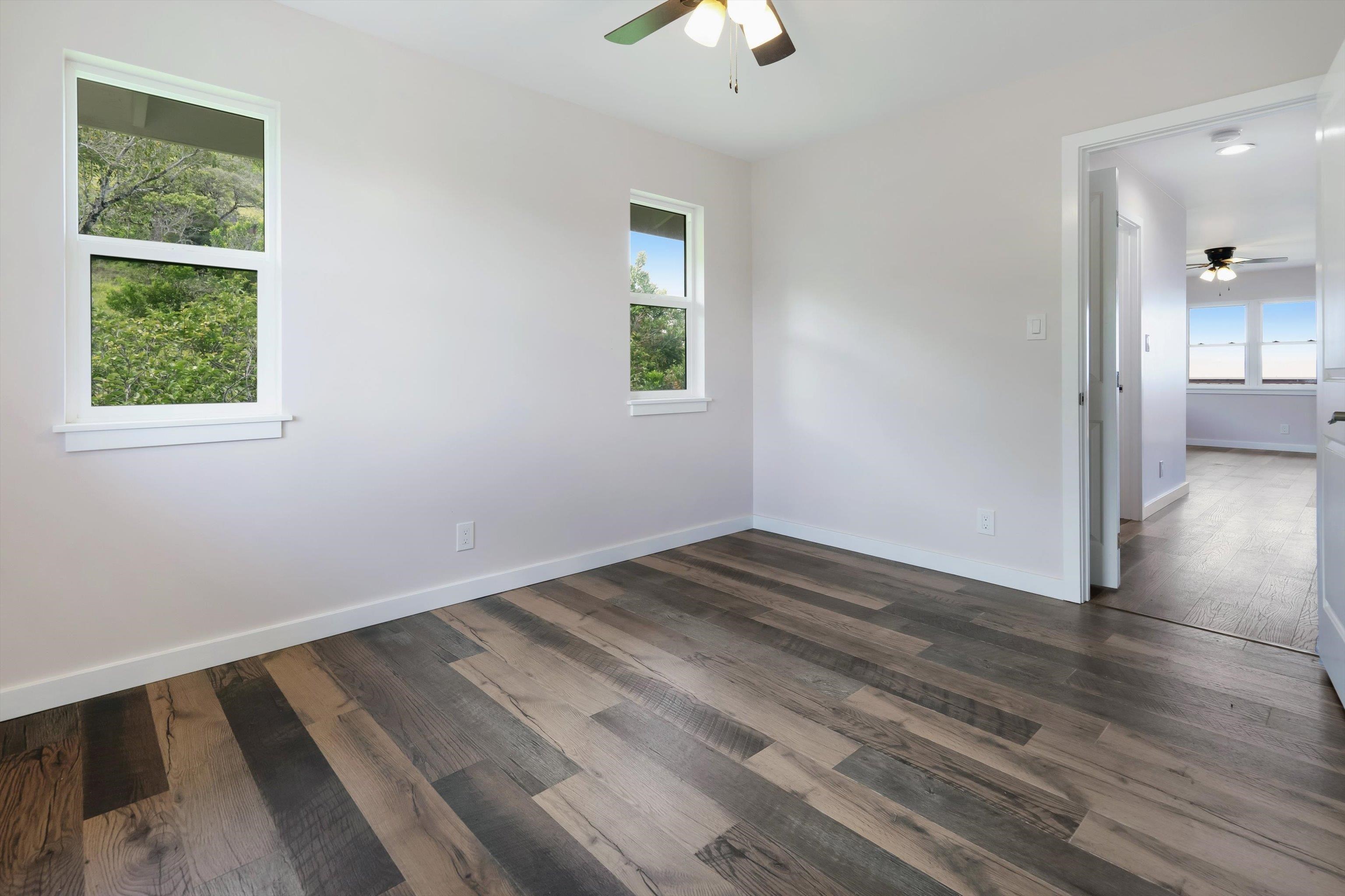 605 Kaupakalua Road Haiku, HI 96708 - Photo 19 of 44 an empty room with wooden floor cabinet and windows