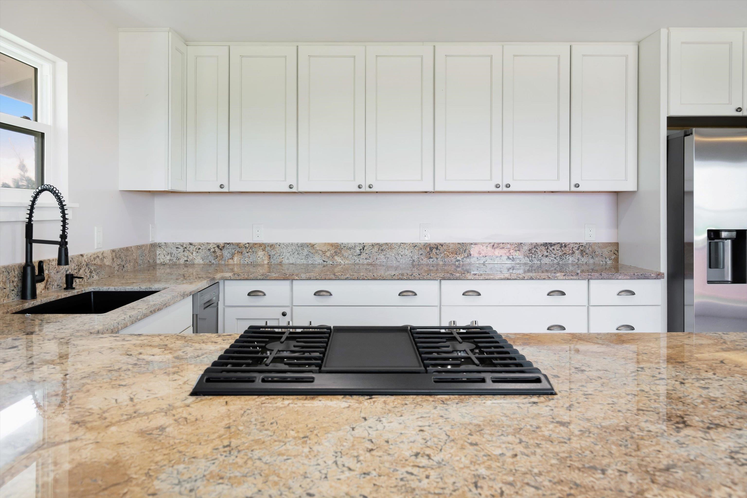 605 Kaupakalua Road Haiku, HI 96708 - Photo 7 of 44 a kitchen with granite countertop a stove a white cabinets a sink and dishwasher