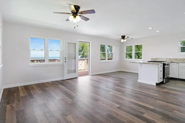 a view of an empty room with window and wooden floor