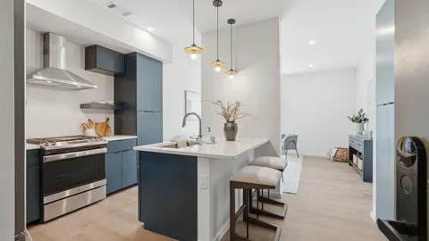 a kitchen with stainless steel appliances kitchen island granite countertop a table chairs in it and wooden floors