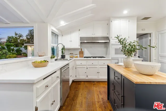 a kitchen with kitchen island a counter top space a sink stainless steel appliances and cabinets
