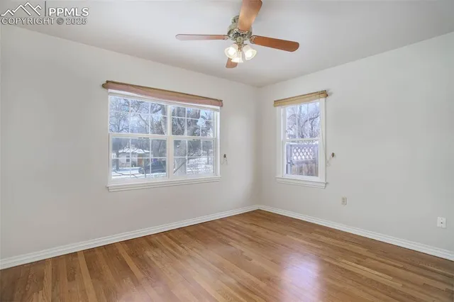 a view of empty room with wooden floor and fan