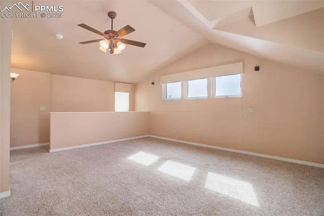 an empty room with a chandelier fan and windows