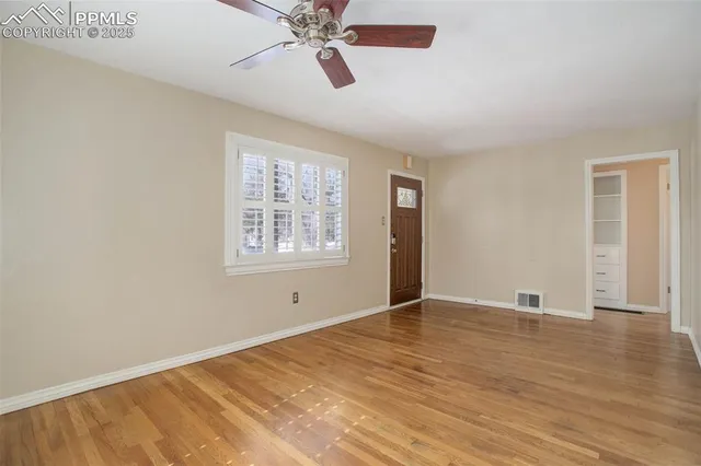 an empty room with wooden floor closet and windows