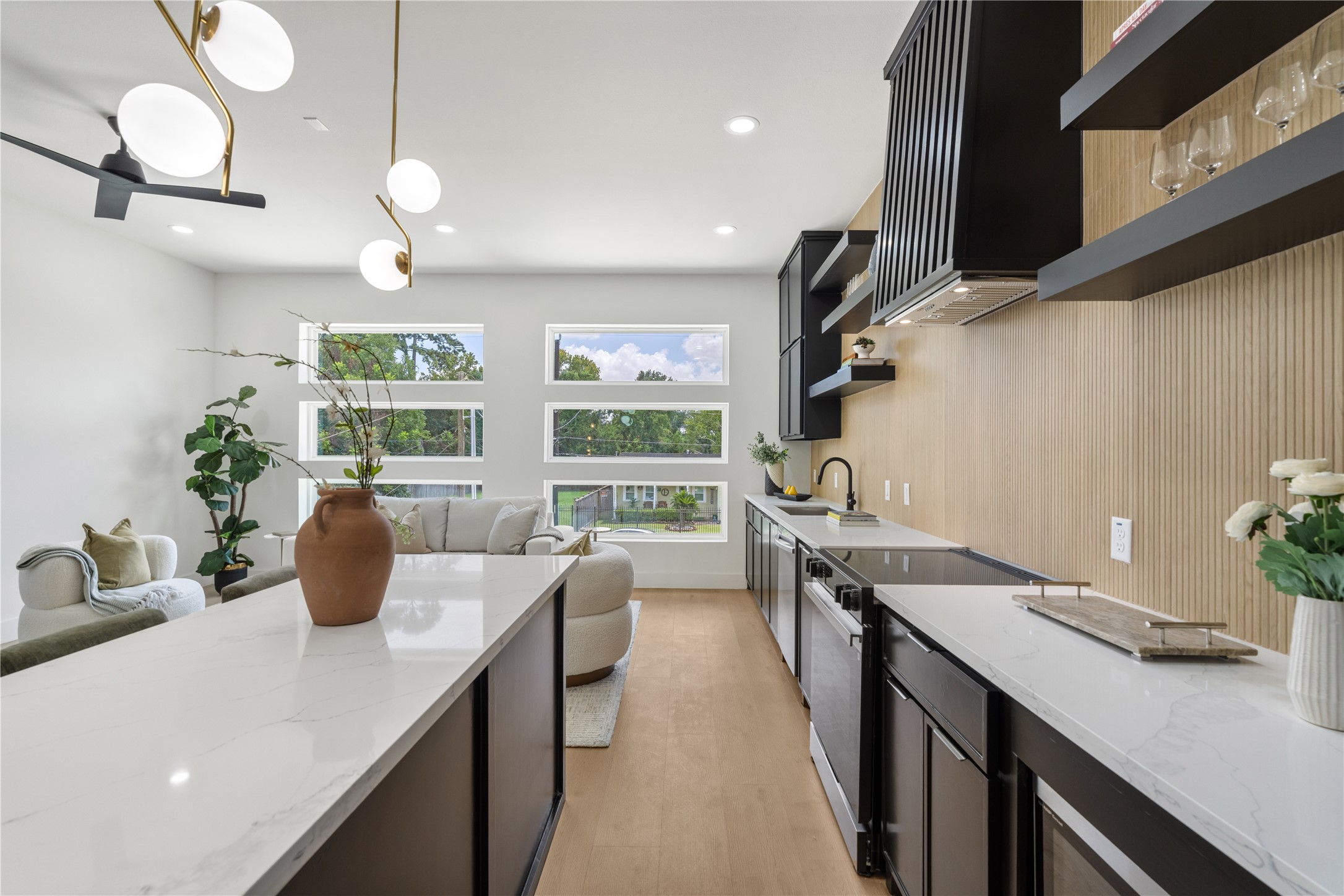 7319 Laura Koppe Road Houston, TX 77028 - Photo 8 of 42 Sleek and modern kitchen with elegant black cabinetry, spacious white countertops, and stylish open shelving. Large windows fill the space with natural light, complementing the contemporary light fixtures and warm wood accents.