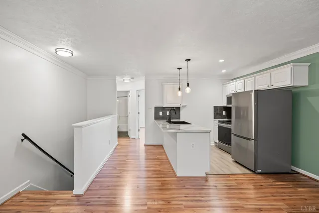 a kitchen with stainless steel appliances a refrigerator a stove a sink and a wooden floor