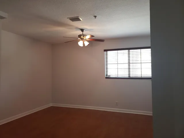 an empty room with windows and fan