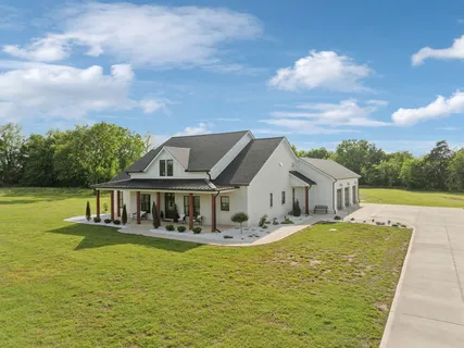 a front view of a house with a garden and trees