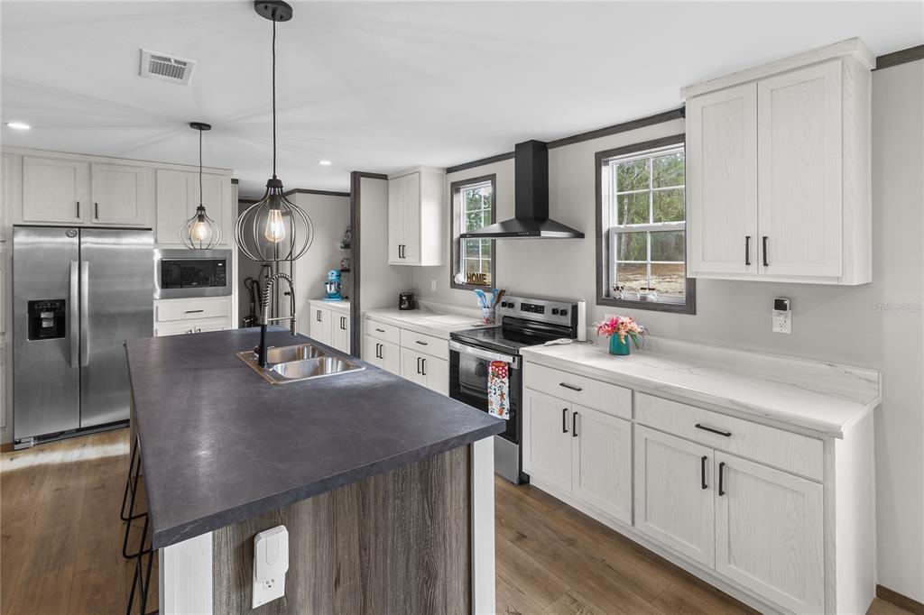 10850 Northeast 110th Lane Archer, FL 32618 - Photo 4 of 24 a kitchen with stainless steel appliances a refrigerator a sink a stove white cabinets and chairs