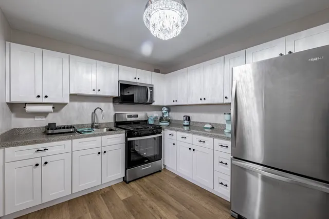 a kitchen with granite countertop white cabinets and white stainless steel appliances