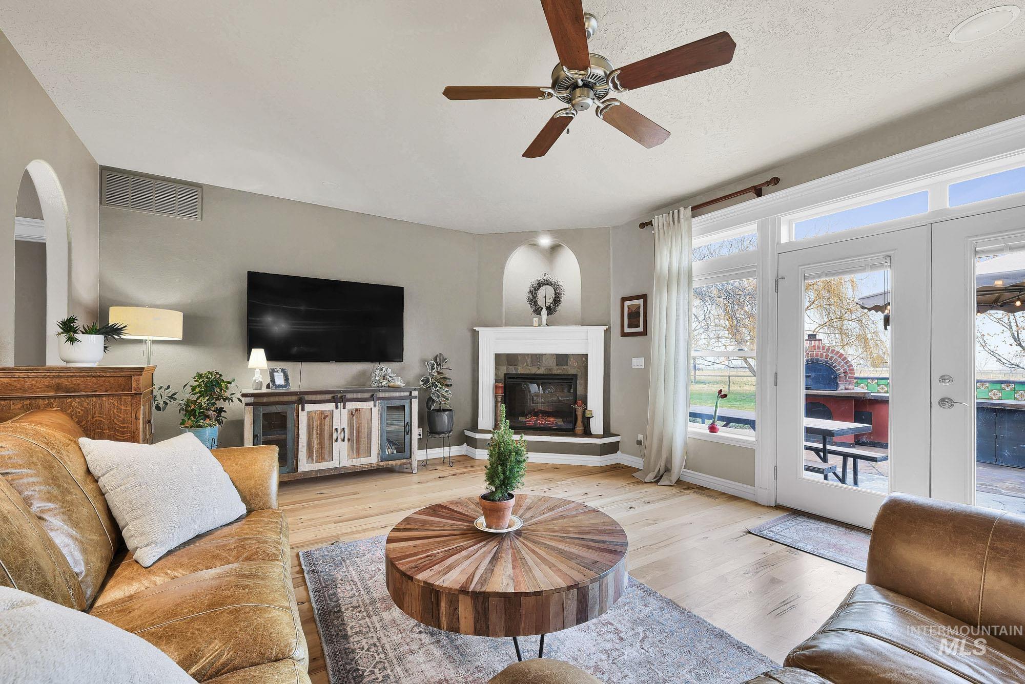 19288 Majestic View Place Caldwell, ID 83607 - Photo 11 of 50 Living room featuring light wood-type flooring, ceiling fan, a tile fireplace, french doors, and arched walkways
