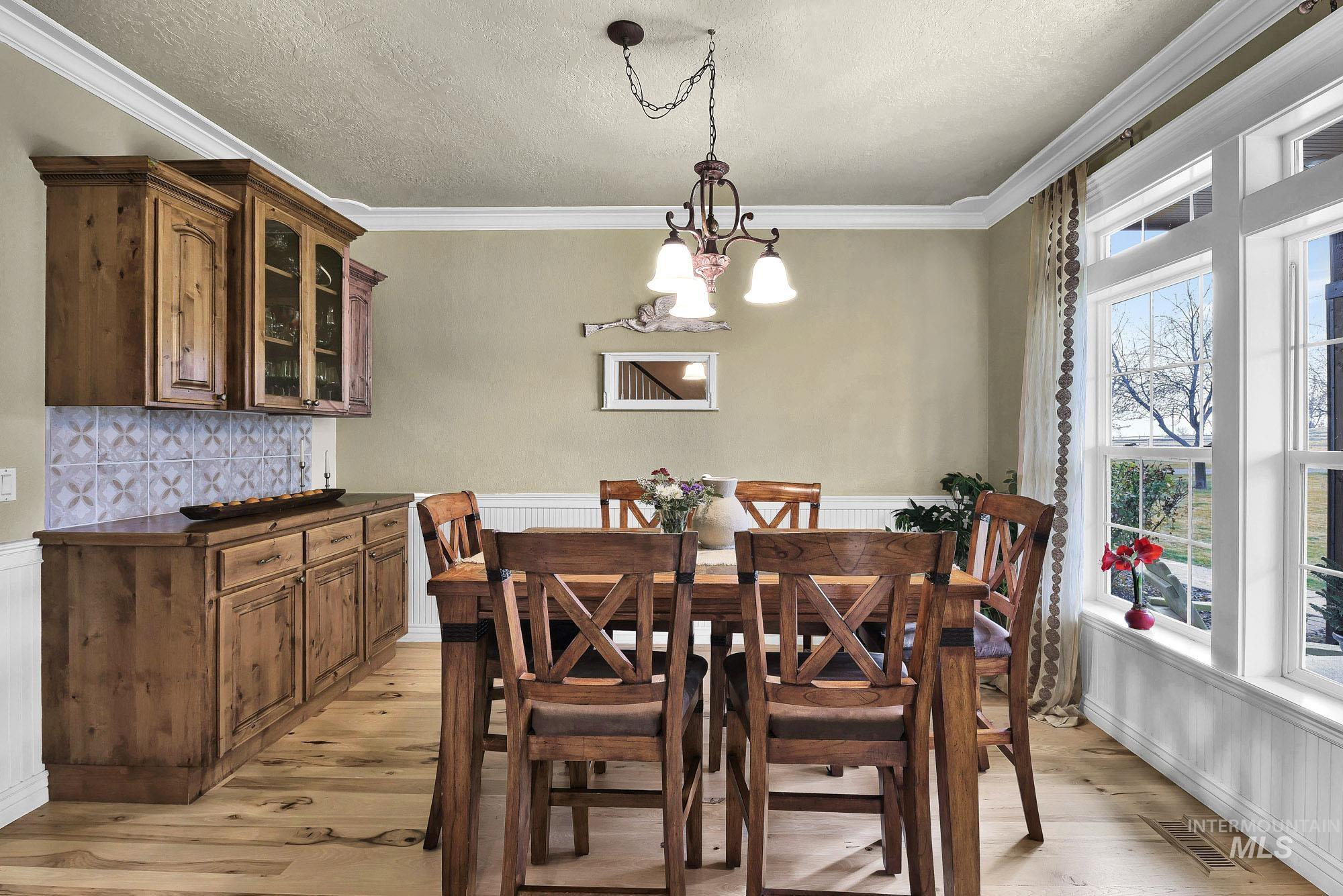 19288 Majestic View Place Caldwell, ID 83607 - Photo 14 of 50 Dining room featuring light wood-style floors, hanging lights, crown molding, a textured ceiling, and wainscoting