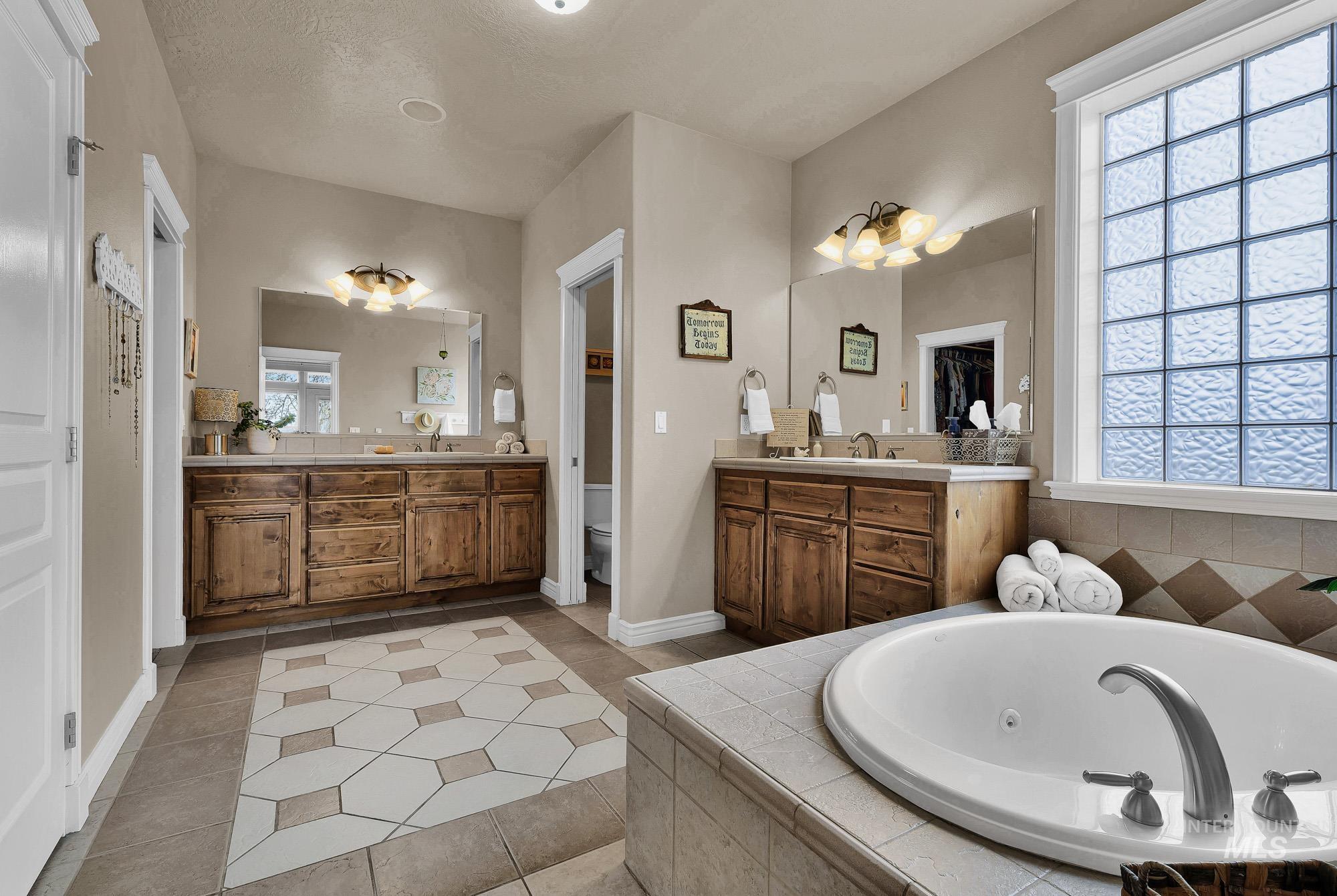 19288 Majestic View Place Caldwell, ID 83607 - Photo 18 of 50 Primary bathroom featuring two vanities, light tile patterned floors, and a jacuzzi tub