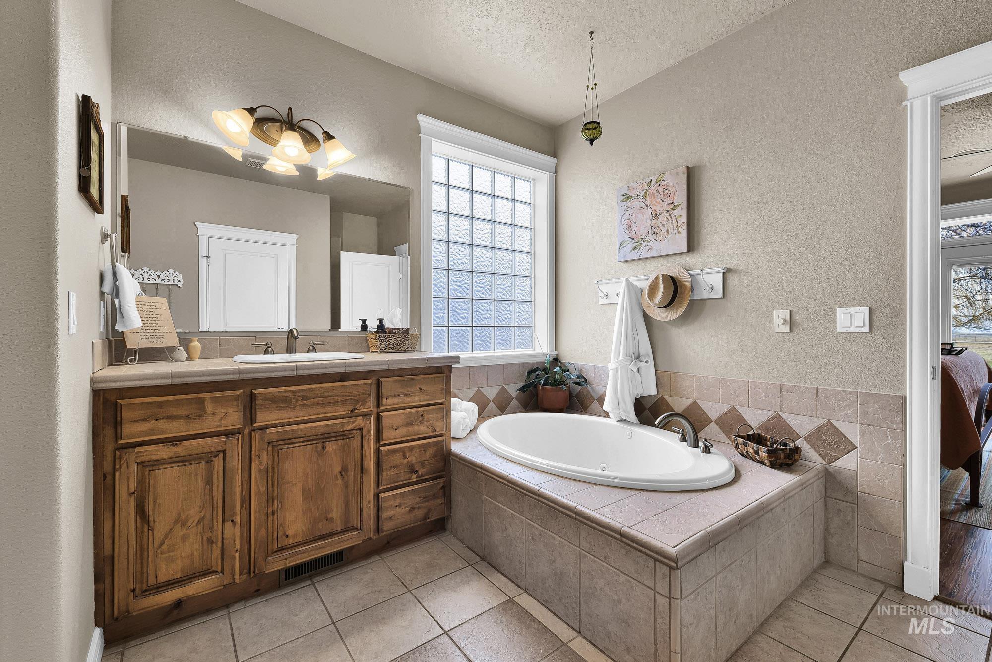 19288 Majestic View Place Caldwell, ID 83607 - Photo 19 of 50 Primary Bathroom featuring dual vanities, a oversized jacuzzi bath, light tile patterned flooring, and huge walk in closet