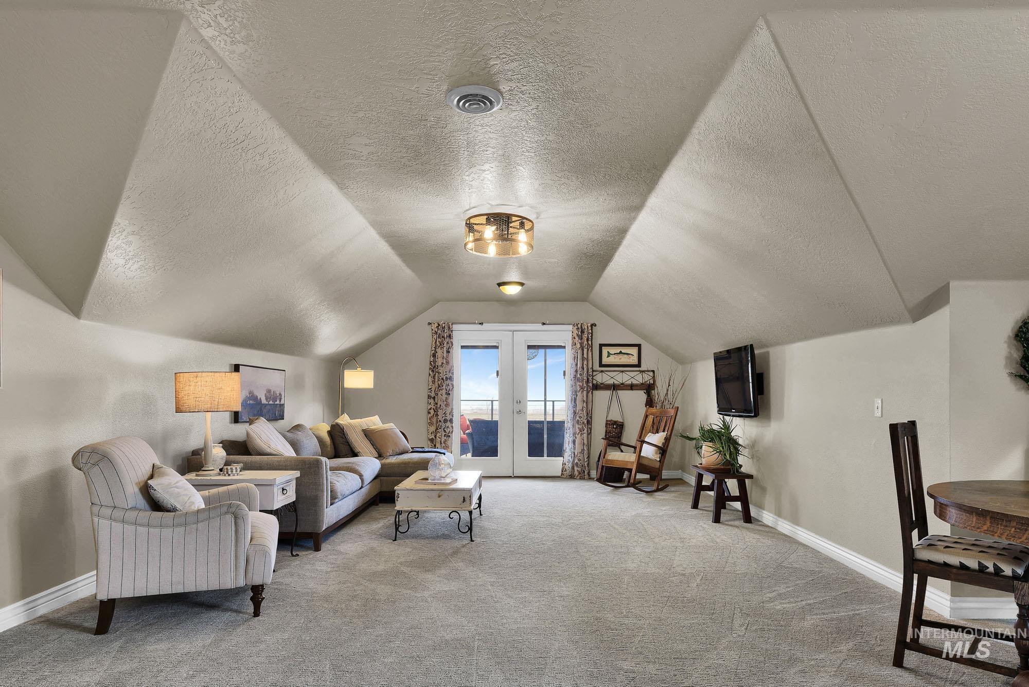 19288 Majestic View Place Caldwell, ID 83607 - Photo 34 of 50 Rec room/ family room featuring an L shaped room with French doors to the covered deck, vaulted ceiling, and light carpet