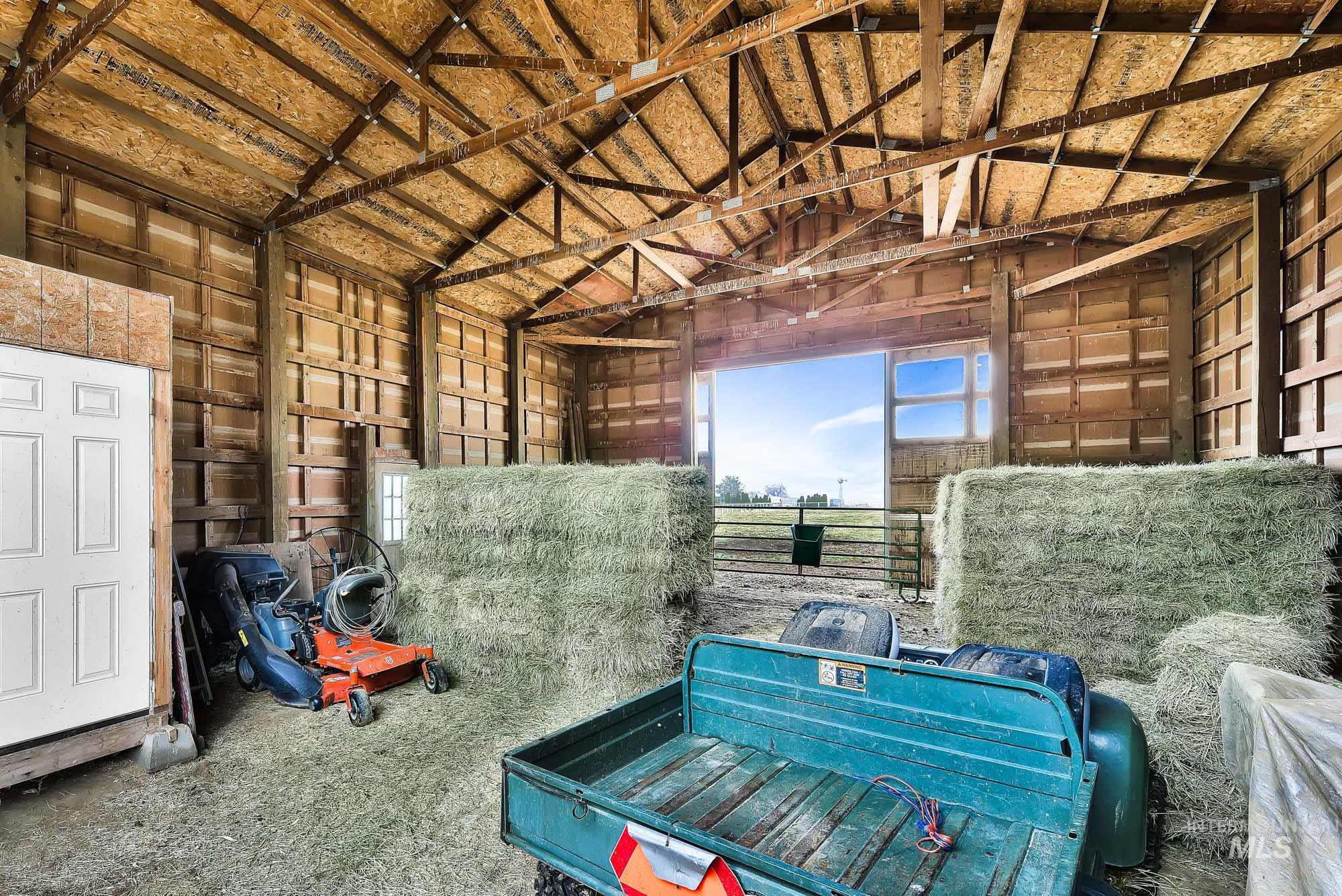 19288 Majestic View Place Caldwell, ID 83607 - Photo 47 of 50 Covered barn area for hay and side tack room featuring lofted ceiling and doors on either end